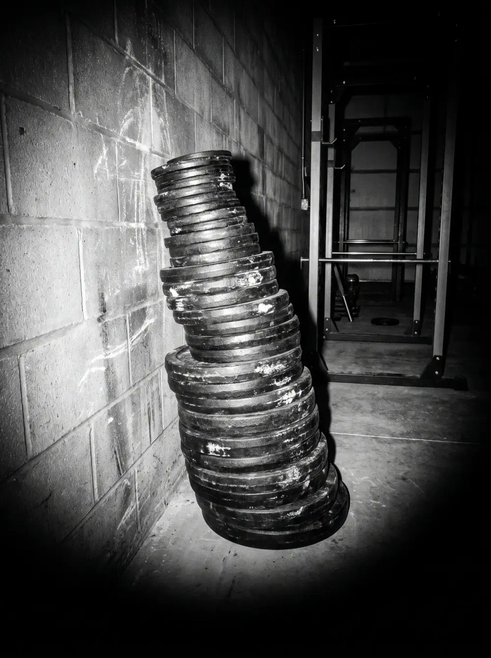 A stack of worn iron plates against a block wall