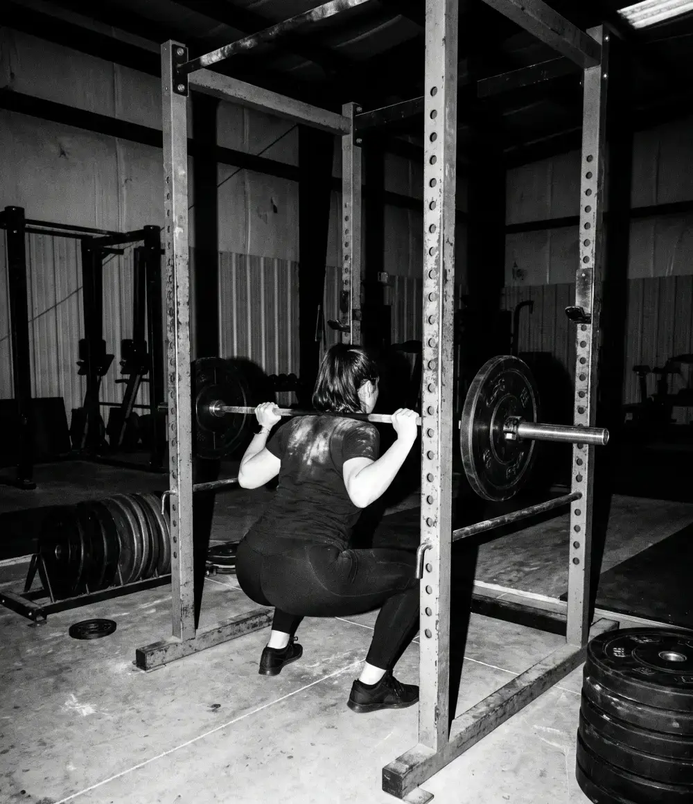 A lifter at the bottom of a back squat, seen from behind