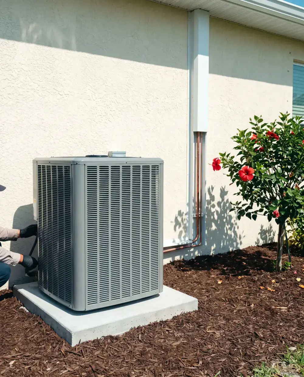 New condenser on a clean pad against a cream stucco wall