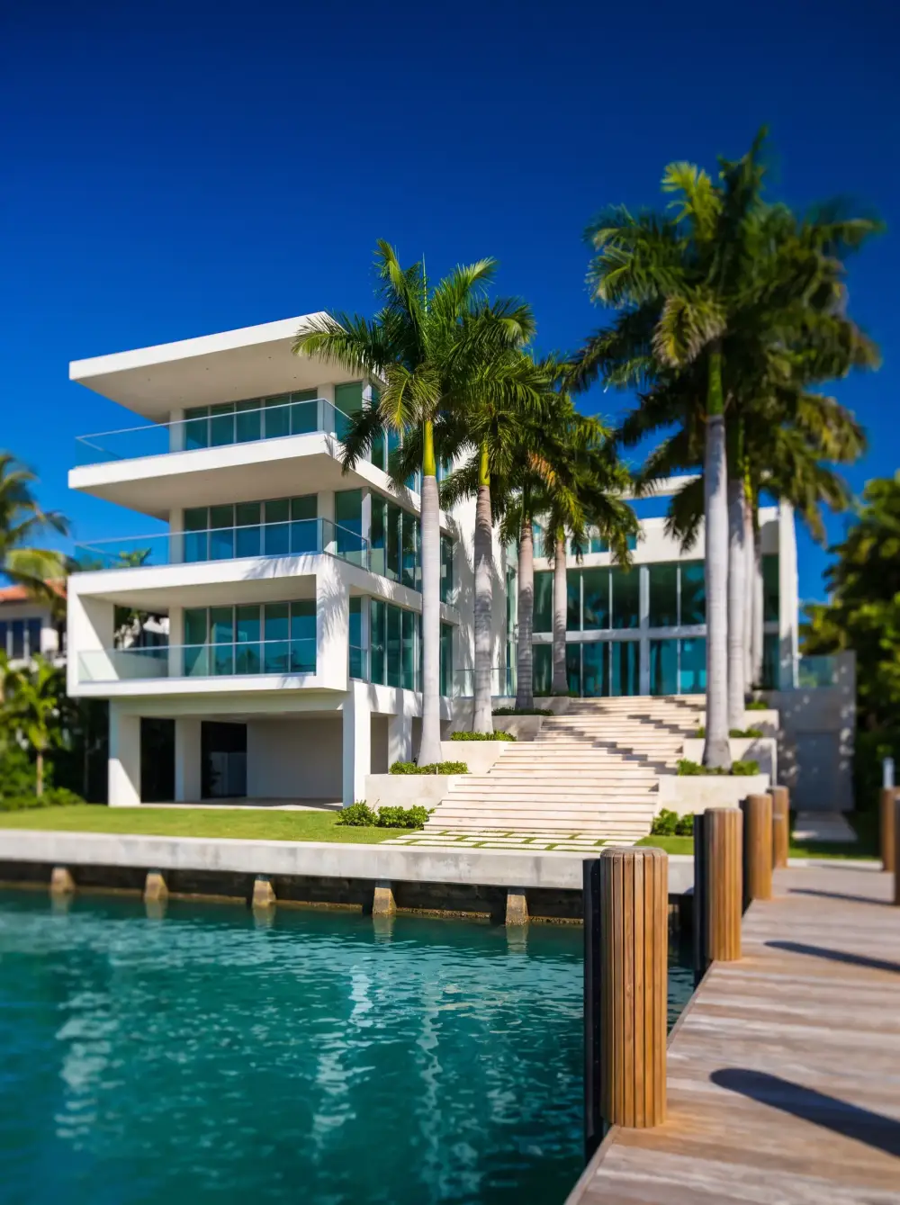 A three-story white estate with cantilevered terraces, seen from its private dock