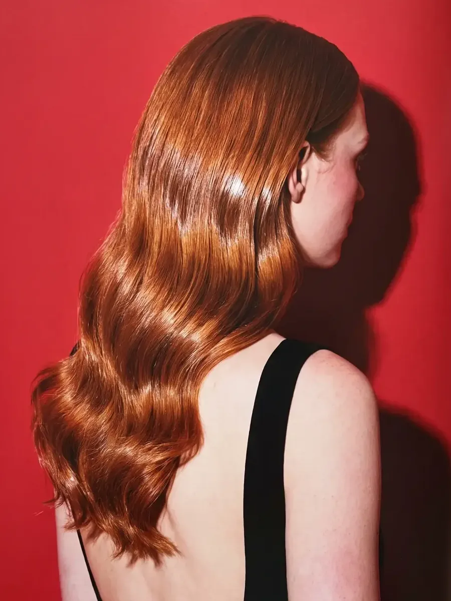 Long copper-red waves seen from behind against a red backdrop, catching the flash.